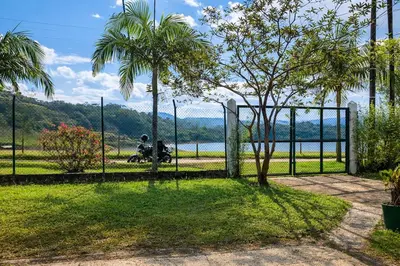 a fence with a palm tree and a person on a motorcycle at Spacious Cabin with Garden and Lake Access, Guatapé in Guatapé