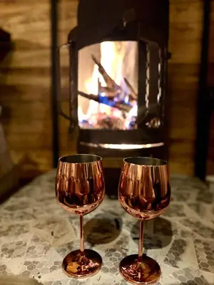 two wine glasses sitting on a table in front of a fireplace at EntreNubes Hospedaje de Alta Montaña
