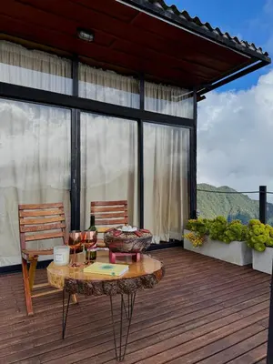 a patio with a table and chairs on a deck at EntreNubes Hospedaje de Alta Montaña