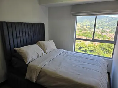 a bed in a bedroom with a large window at Modern sky high apartment in La Estrella in La Estrella