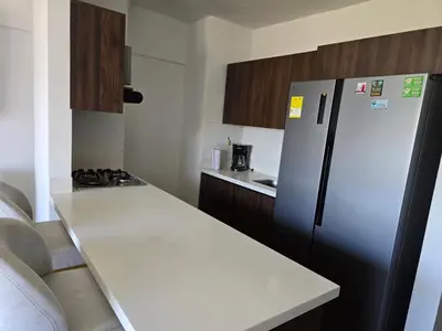 a kitchen with a white counter and a refrigerator at Modern sky high apartment in La Estrella in La Estrella
