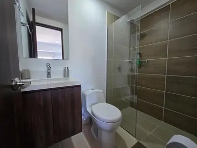 a bathroom with a toilet and a glass shower at Modern sky high apartment in La Estrella in La Estrella