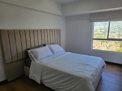a bedroom with a bed with white sheets and a window at Modern sky high apartment in La Estrella in La Estrella