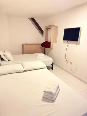 a hotel room with two beds and a flat screen tv at Hotel California Blue Manizales in Manizales