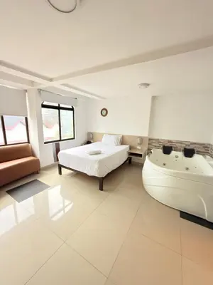 a bedroom with a bed and a bath tub next to a bed at Hotel California Blue Manizales in Manizales