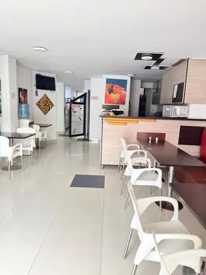 a kitchen with white chairs and tables and cabinets at Hotel California Blue Manizales in Manizales