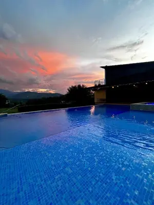 a large swimming pool with a sunset in the background at FIincaVilla Cavil a 50 min de Medellin in Sopetran
