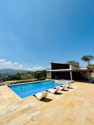 a row of white lounge chairs next to a swimming pool at FIincaVilla Cavil a 50 min de Medellin in Sopetran