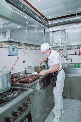a woman standing in a kitchen preparing food at Hostel North SAS in Medellín