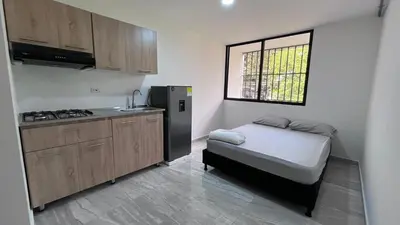 a small kitchen with a small refrigerator and a table at Acogedor Loft Medellin cerca al Estadio Atanasio in Medellín