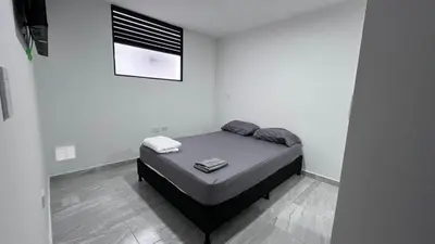 a bedroom with a bed in a white room at Alojamiento entero loft en Medellin, Estadio in Medellín