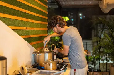 a man preparing food in a pot on a stove at Co404 Medellin - Coliving Coworking in Medellín