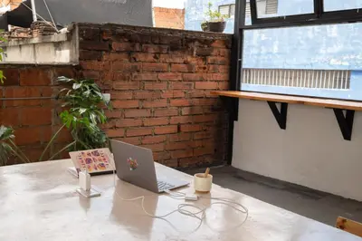a laptop sitting on a table next to a brick wall at Co404 Medellin - Coliving Coworking in Medellín