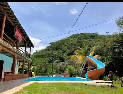 a slide in a pool in front of a building at Finca Mi Delirio in Cocorná