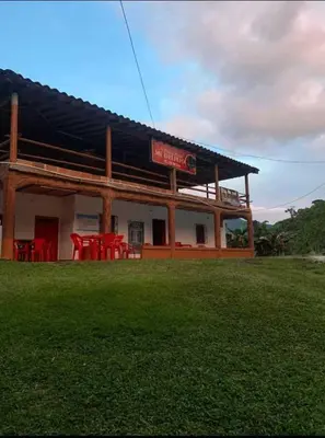 a building with a table and chairs in a field at Finca Mi Delirio in Cocorná