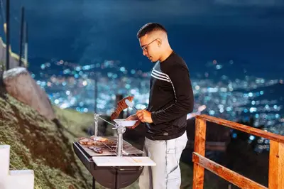 a young man is cooking food on a grill at Charlotte Alojamiento in Medellín