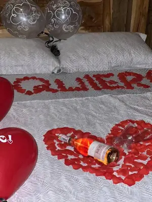 a bed with a heart with a bottle of wine on it at Green view glamping cabin with unlimited Jacuzzi in Cocorná