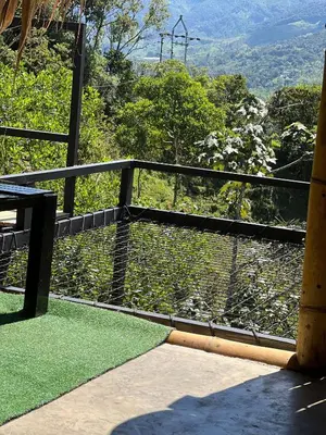 a balcony with a bench and a view of a mountain at Green view glamping cabin with unlimited Jacuzzi in Cocorná