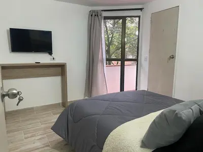a bedroom with a bed and a tv and a window at exclusive pink zone sabaneta friends and fun in Sabaneta