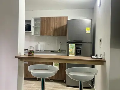 a kitchen with two bar stools and a refrigerator at exclusive pink zone sabaneta friends and fun in Sabaneta