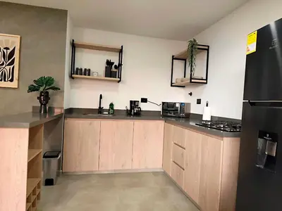 a kitchen with wooden cabinets and a black refrigerator at Edificio OA Aparta-suites in Medellín