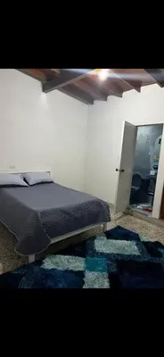 a bedroom with a bed with a blue rug and a mirror at Hostel La Casona in Medellín