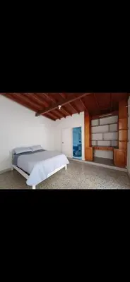a bedroom with a large bed and a room with at Hostel La Casona in Medellín