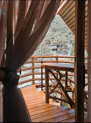 a wooden deck with a table and a curtain at La Chorrera ecohotel in Cocorná