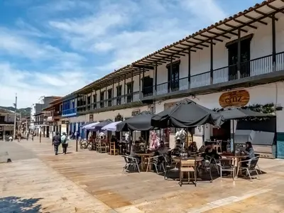 a patio with tables and chairs and umbrellas on a street at Habitación con cama nueva doble y balcón privado cerca del parque principal in La Ceja
