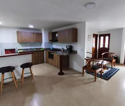a kitchen with wooden cabinets and a table and chairs at Habitación con cama nueva doble y balcón privado cerca del parque principal in La Ceja