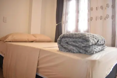 a blanket sitting on top of a bed at Habitación con cama nueva doble y balcón privado cerca del parque principal in La Ceja