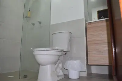 a bathroom with a white toilet and a shower at Cama nueva doble con balcón cerca del parque principal in La Ceja