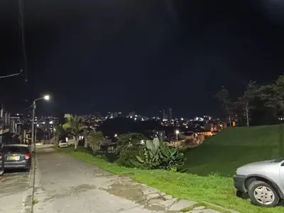 a city street at night with cars parked on the road at Hostal Villa Café in Manizales
