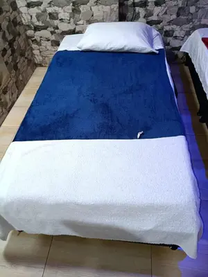 a bed with a blue and white blanket on it at Hostal Villa Café in Manizales