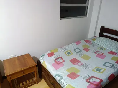 a bed with a quilt on it next to a table at Hostal Villa Café in Manizales
