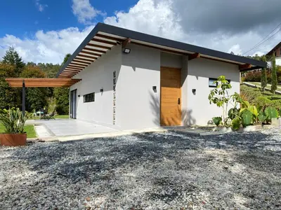 a white house with a driveway in front of it at Santa Elena casa pino in Medellín