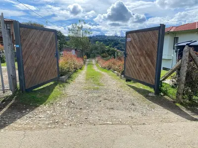 a pair of wooden gates on a dirt road at Santa Elena casa pino in Medellín