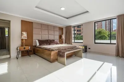 a bedroom with a bed and a table and windows at Ph volcana in Medellín