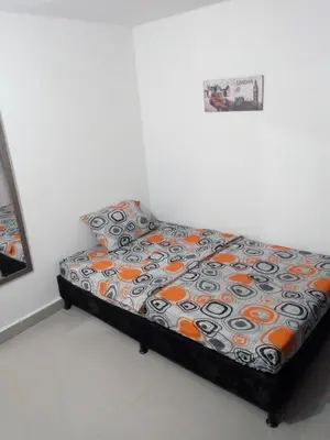 a bedroom with a bed with an orange and black comforter at VILLA La May in Medellín