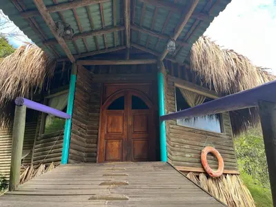 a house with a wooden door and a thatch roof at Finca Hotel Mariangel in El Peñol