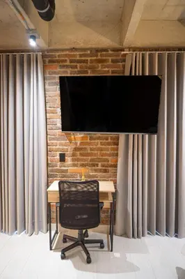 a desk with a chair and a television on a brick wall at Estrena Apto Moderno para Viajeros con Estilo in Medellín