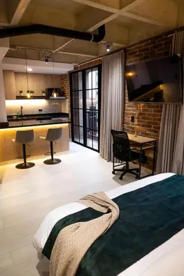 a bedroom with a bed and a kitchen and a desk at Estrena Apto Moderno para Viajeros con Estilo in Medellín