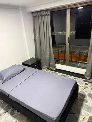 a bed in a room with a large window at Tu alojamiento parque caldas in Manizales