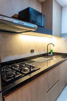a kitchen with a stove and a sink and a microwave at Stylish Laureles Apartment, New Apartment in Medellín