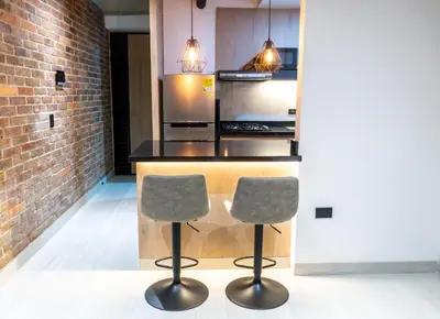 a kitchen with two bar stools in front of a counter at Stylish Laureles Apartment, New Apartment in Medellín