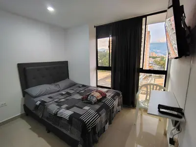 a bedroom with a bed and a table and a window at Apartamento loft amoblado Medellin in Medellín