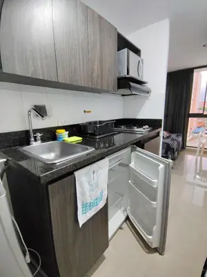 a kitchen with a sink and an open refrigerator at Apartamento loft amoblado Medellin in Medellín