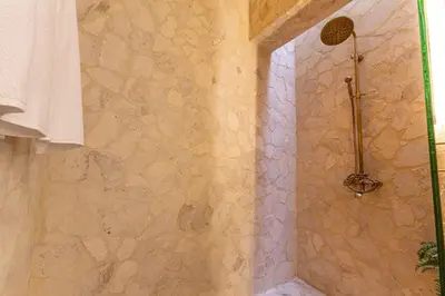 a bathroom with a shower with a stone wall at Casa Museo Living by HOUSY in Medellín