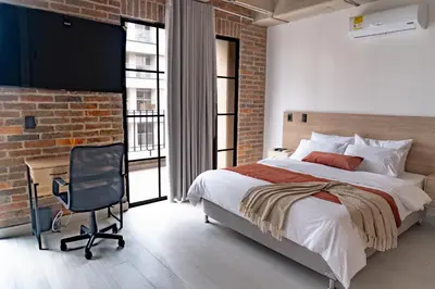 a bedroom with a brick wall and a bed and a desk at Brand New Premium Apartment with Large Balcony in Medellín