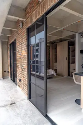 a brick wall with sliding glass doors in a room at Brand New Premium Apartment with Large Balcony in Medellín